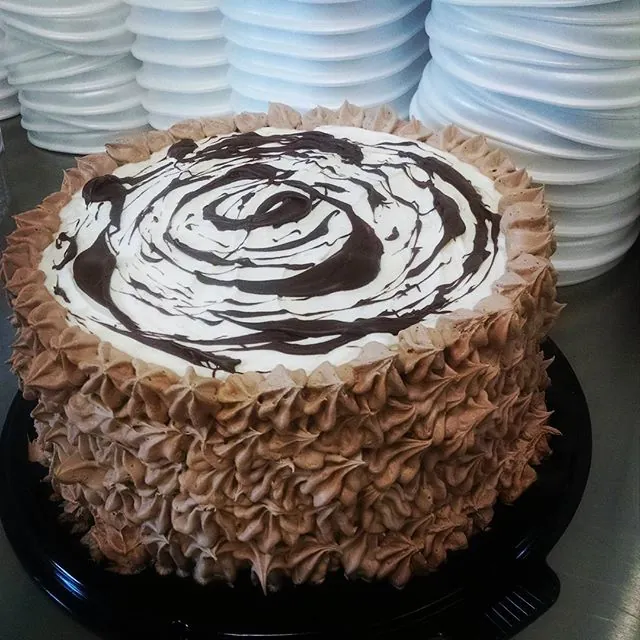 A round gelato cake covered in piped chocolate rosettes, a dark chocolate swirl on top