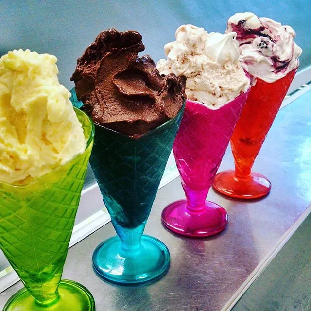 Four coloured glass coupes of gelato on a steel counter