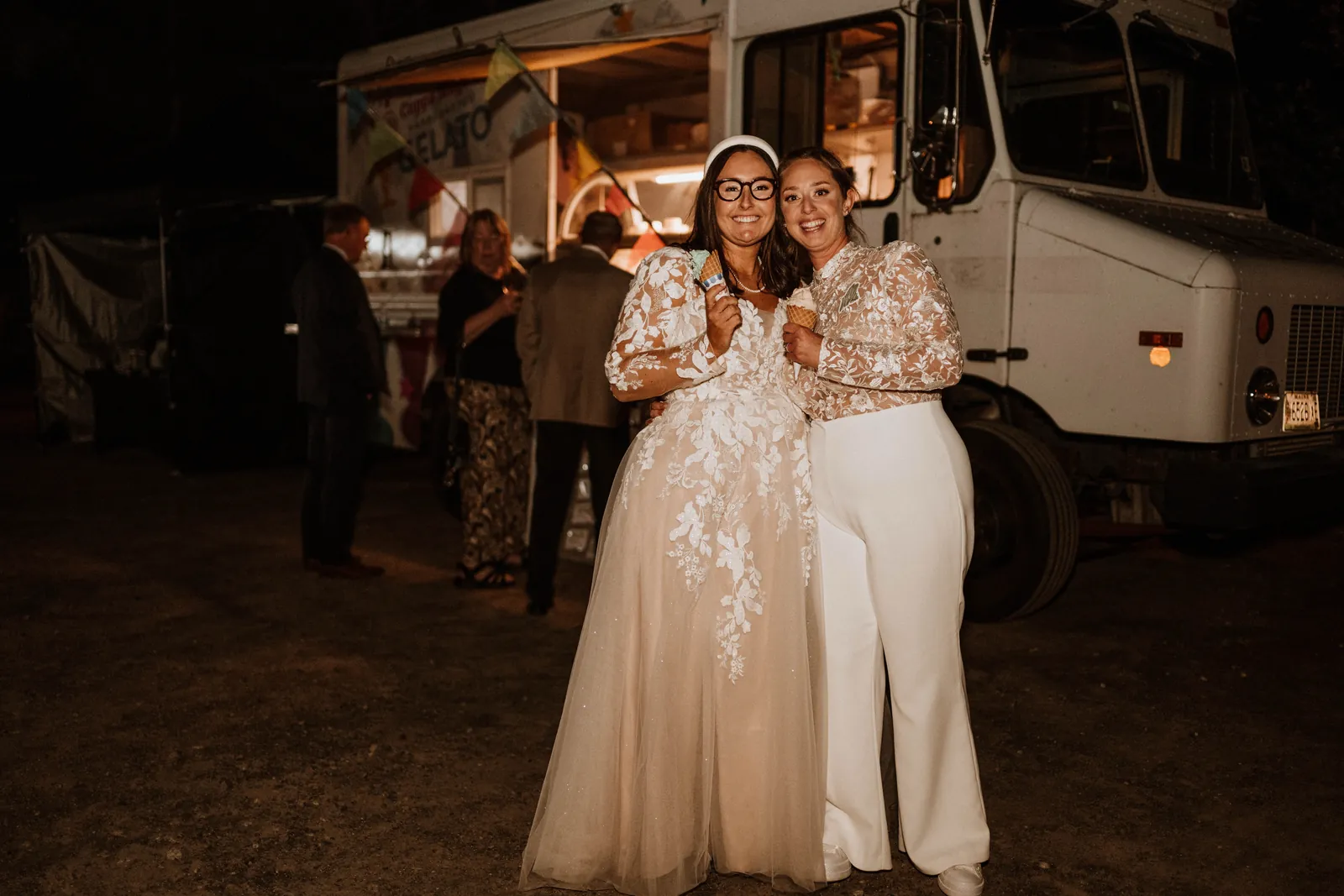 A newly married couple smiling in front of the lit-up Coppa Magica truck at night